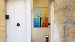 A white door with a black handle, leading to a room with a colorful painting of a tree.