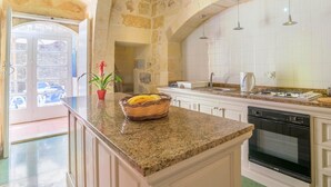 A kitchen with stone walls, a granite countertop, a stove, and a sink.