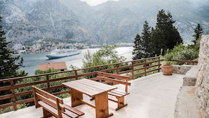 Una terrazza in legno con panchine che si affaccia su un lago e una cittadina.