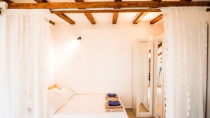 Una camera da letto con soffitto in legno, un letto con lenzuola bianche e un piccolo tavolo con asciugamani.