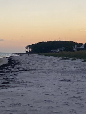 Ein Strand mit einem Steg und Häusern im Hintergrund.