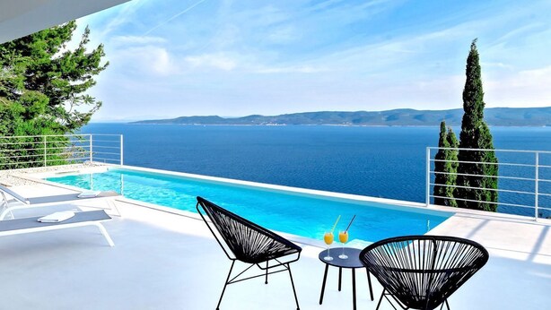 A poolside area with a view of the sea, two lounge chairs, and a table with drinks. - Villa Dinara - Three Bedroom Villa, Sleeps 6 (Mimice)