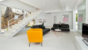 A modern living room with a staircase, black sofas, a yellow armchair, and a large TV. - Villa Dinara - Three Bedroom Villa, Sleeps 6 (Mimice)