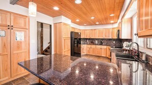 Eine moderne Küche mit Holzschränken, Granit-Arbeitsplatten und einem Edelstahl-Kühlschrank.