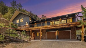 Ein zweistöckiges Haus mit Steinaußenwand, einer Holzterrasse und einer Garage.