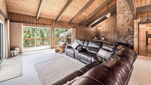 Ein geräumiges Wohnzimmer mit einer Ledersofa, Holzbalkendecke und einer Wand mit Steinverkleidung.