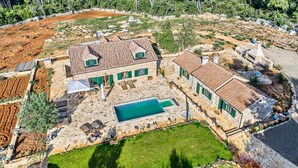 A stone house with a swimming pool, surrounded by a well-maintained garden and a large field. - Old Town Villa Hvar - Five Bedroom Villa, Sleeps 12 (Uvala Tatinja)