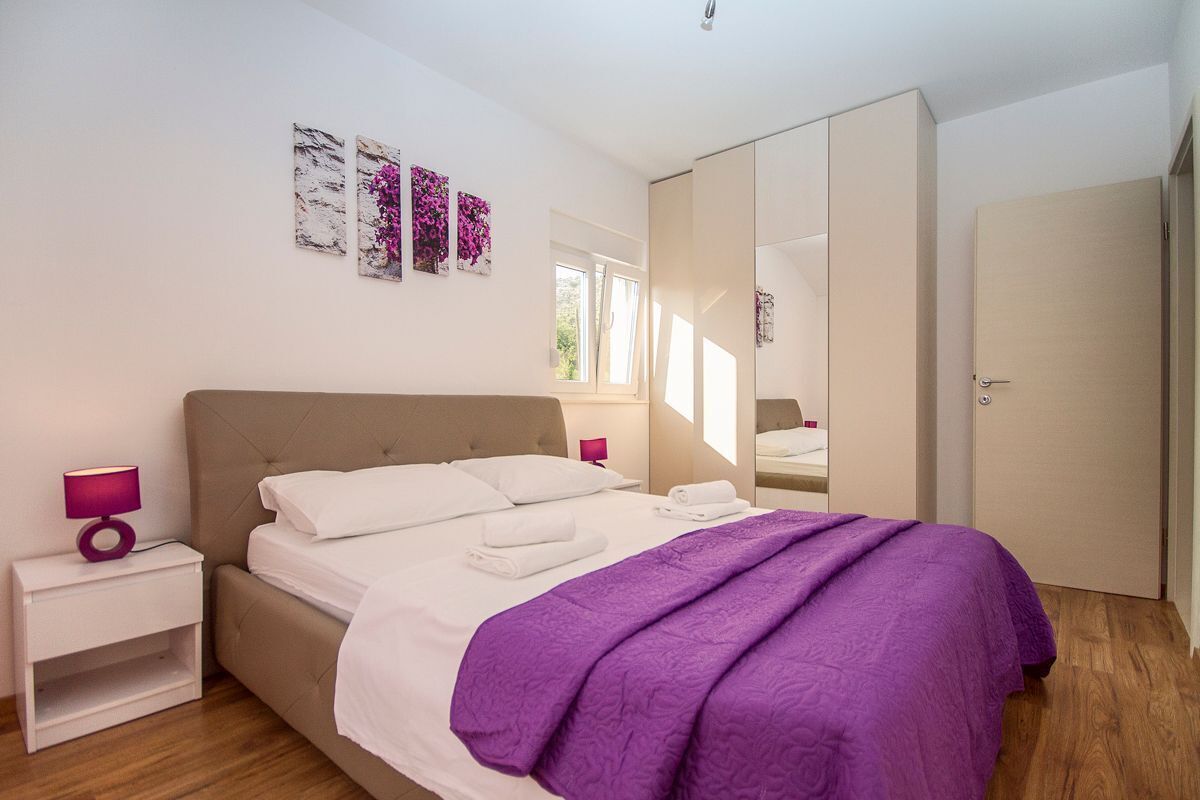 Een slaapkamer met een bed, nachtkastjes, een kledingkast en kunst aan de muur.