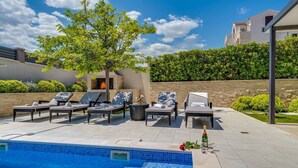 A swimming pool with lounge chairs and a small fire feature.