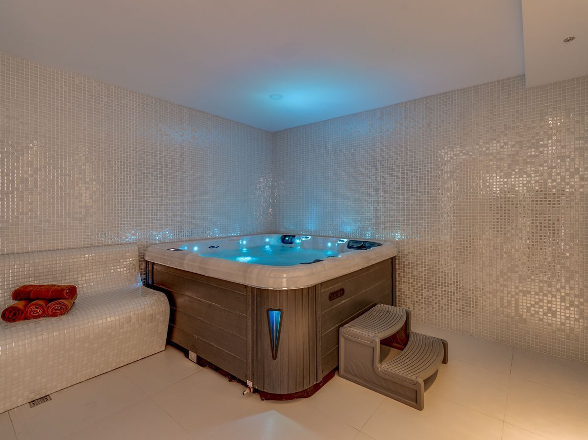 A modern bathroom with a hot tub, a bench, and a small stool.
