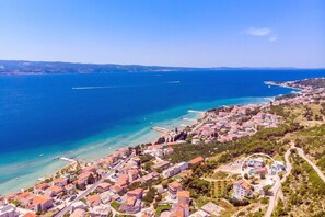 An aerial view of a coastal town with buildings, roads, and a clear blue sea.