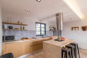 Una cucina moderna con mobili in legno, forno a microonde integrato, cappa aspirante in acciaio inox e un'ampia finestra.