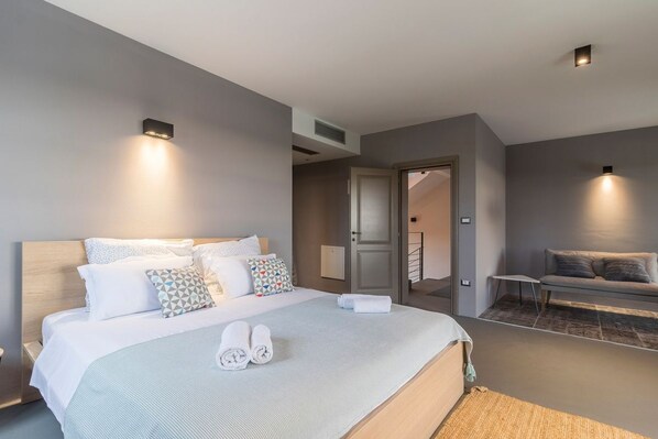 Una habitación de hotel moderna con una cama grande, un sofá y dos luces fijadas a la pared.