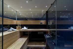A modern sauna with wooden benches, a wooden table with towels, and a glass wall offering a view of the cityscape. - Villa Novi - Five Bedroom Villa, Sleeps 12 (Rudine)