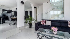 A modern living room with a black sofa, glass coffee table, and a potted plant. - Villa Novi - Five Bedroom Villa, Sleeps 12 (Rudine)
