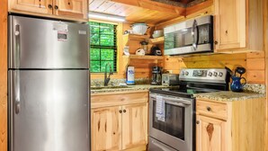 Una cocina con armarios de madera, electrodomésticos de acero inoxidable, un microondas, una estufa y un lavaplatos.
