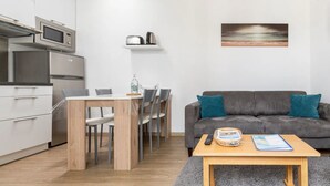 Un espacio moderno para vivir con cocina, comedor y un sofá gris con cojines turquesa.