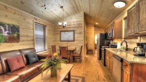 A cozy cabin interior with a wooden interior, a dining area, and a kitchen with modern appliances. - Hook, Line & Sinker: Perfect Cabin Nestled in Woods Only Minutes from Gatlinburg Strip (Gatlinburg)
