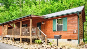 A wooden cabin with a porch, a staircase, and a sign indicating it is a cabin. - Fish Tales: Cozy Cabin Perfect for Family Getaway (Gatlinburg)