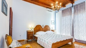 A bedroom with a wooden bed, a nightstand, a chair, and a chandelier. - Villa Lyubov - Three Bedroom Villa, Sleeps 9 (Tisno)