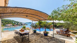 An outdoor patio with a table and chairs, a pool, lounge chairs, and a view of the sea. - Villa Lyubov - Three Bedroom Villa, Sleeps 9 (Tisno)
