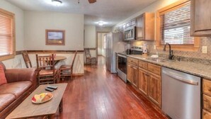 A spacious kitchen with wooden cabinets, a stainless steel dishwasher, and a granite countertop. - Gone Fishing: Secluded Cabin in Woods Overlooking Beautiful Mountain Stream (Gatlinburg)