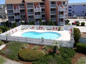 Relax by the hotel's rectangular pool surrounded by lush greenery and a white picket fence.