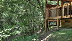 Eine Holzhütte mit einem Balkon mit Blick auf einen bewaldeten Bereich.
