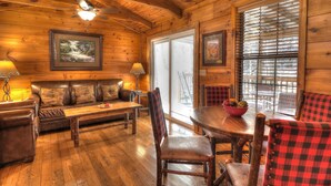 A cozy cabin interior with a wooden ceiling, a sofa, a dining table, and chairs. - Oakview: Pet-Friendly Cabin Nestled in a Secluded Wooded Area Only Minutes from Downtown Gatlinburg (Gatlinburg)