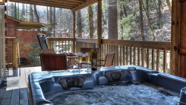 A hot tub on a wooden deck with a view of a forest. - Oakview: Pet-Friendly Cabin Nestled in a Secluded Wooded Area Only Minutes from Downtown Gatlinburg (Gatlinburg)