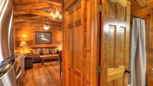 A wooden interior with a sofa, a table, and a chandelier. - Oakview: Pet-Friendly Cabin Nestled in a Secluded Wooded Area Only Minutes from Downtown Gatlinburg (Gatlinburg)