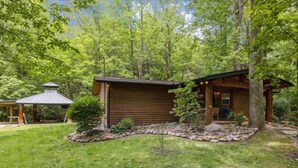 Une cabane en bois dotée d’un porche abrité, entourée d’un sentier pavé de pierres et d’une végétation luxuriante.