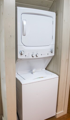 Een witte wasmachine met bedieningspaneel, geplaatst in een houten kast.