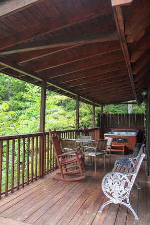 Relax on the deck with a hot tub, wooden table, and comfortable seating.