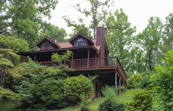 Escape to a secluded cabin nestled in a lush forest, featuring a charming front porch and a unique elevated view.