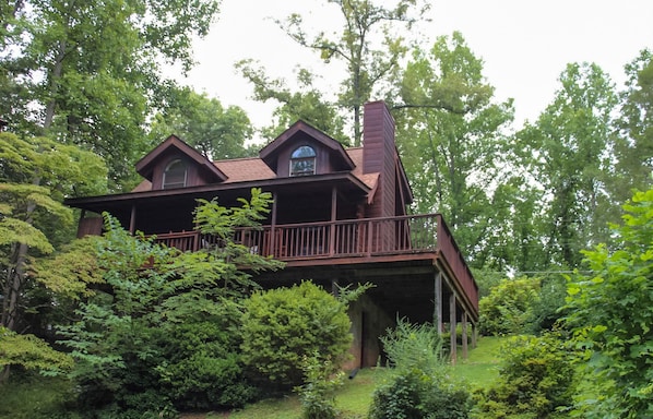 Escape to a secluded cabin nestled in a lush forest, featuring a charming front porch and a unique elevated view.