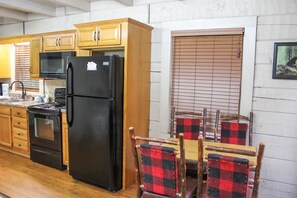 Cozy kitchen area with a dining table and four chairs, a stove, sink, and refrigerator.