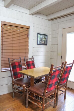 A dining area with a wooden table and four chairs with plaid upholstery.