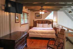 Cozy bedroom with a large bed, wooden headboard, and sloped ceiling.