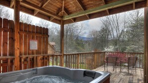 Un jacuzzi en una terraza de madera con valla y sillas.