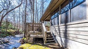 A cabin with a wooden deck and steps leading to a porch.