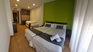 Una habitación de hotel con dos camas, un escritorio, una silla y una pared verde decorativa.