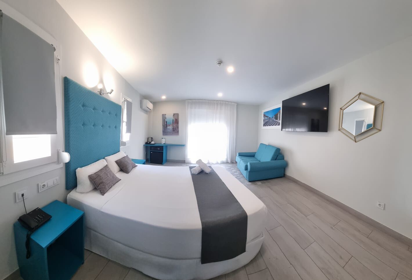 Ein modernes Hotelzimmer mit einem großen Bett, einem Schreibtisch, einer Couch und einem Essbereich.