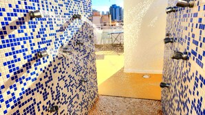 A bathroom with blue and white mosaic tiles, a shower area, and a visible drain. - Hotel Clopy Rocamar (Benidorm)