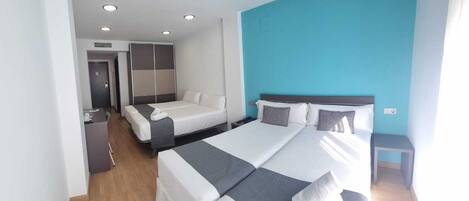 A modern hotel room with two beds, a desk, and a wardrobe.