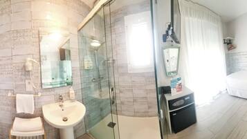 A modern bathroom with a glass shower enclosure, a white sink, and a toilet.