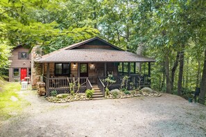 A rustic cabin with a stone foundation, a wooden porch, and a gravel driveway. - Wildflower Haven: Beautiful Secluded Cabin in Gatlinburg, Just Minutes from Downtown Gatlinburg. (Sevierville)