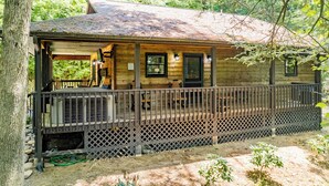 A wooden cabin with a porch and lattice railing. - Wildflower Haven: Beautiful Secluded Cabin in Gatlinburg, Just Minutes from Downtown Gatlinburg. (Sevierville)