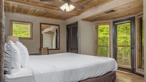 Ein Schlafzimmer mit Bett, Deckenventilator und einem großen Fenster mit Jalousien.
