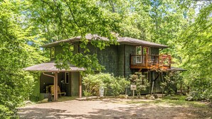 Eine rustikale Holzhütte mit Veranda, umgeben von dichtem Grün.